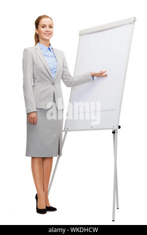 Business, istruzione e concetto di ufficio - imprenditrice sorridente in piedi accanto al flip board e mano di puntamento Foto Stock