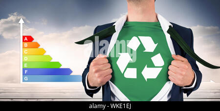 Imprenditore maglietta di apertura in stile supereroi contro il grafico che mostra l'energia nominale grafico Foto Stock