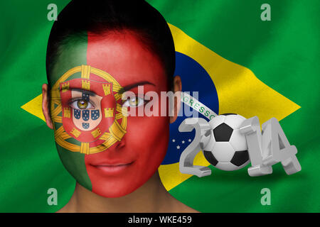 Immagine composita del Portogallo appassionato di calcio in faccia vernice contro di coppa del mondo 2014 con brasil bandiera Foto Stock