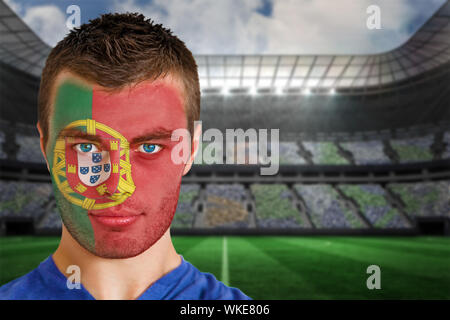 Immagine composita del Portogallo appassionato di calcio in faccia vernice contro grande stadio di calcio sotto i faretti Foto Stock