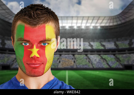 Immagine composita del Camerun appassionato di calcio in faccia vernice contro grande stadio di calcio sotto i faretti Foto Stock