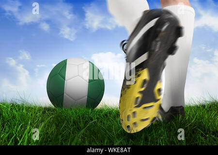 Immagine composita di scarpa da calcio calci nigeria sfera contro campo di erba sotto il cielo blu Foto Stock