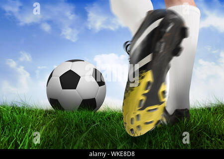 Immagine composita di scarpa da calcio calci palla contro campo di erba sotto il cielo blu Foto Stock