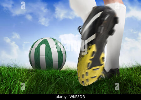 Immagine composita di scarpa da calcio calci nigeria sfera contro campo di erba sotto il cielo blu Foto Stock