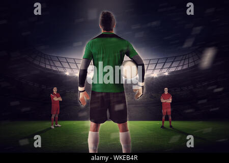 Immagine composita di goalie rivolta verso l opposizione contro il grande stadio di calcio con ventole in giallo Foto Stock