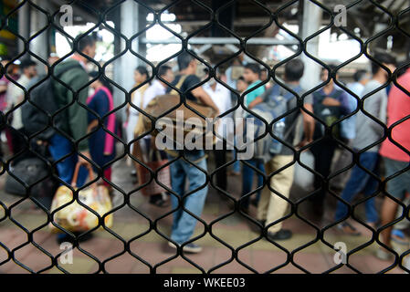 INDIA, Mumbai, stazione ferroviaria suburbana di treno pendolari Western Railway WR, viaggio pendolari tra suburbani e centro città, vista dalla finestra del treno bloccato, molti passeggeri sulla piattaforma Foto Stock