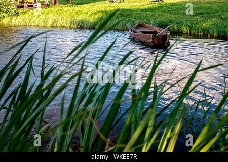 Una piccola barca a remi in legno barca con una rotta sul fondo di un lago calmo vicino alla riva. Bielorussia Foto Stock