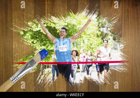 Immagine composita del corridore di attraversamento della linea di finitura con pennello immerso nel blu contro la superficie di legno con tavole Foto Stock