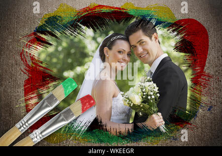 Immagine composita di sposi sorridente in telecamera con pennello immerso in rosso contro la superficie spiovente Foto Stock