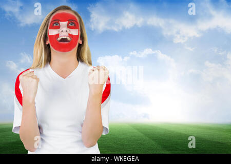 Ventola eccitato in Svizzera di vernice faccia il tifo contro il calcio sotto il cielo blu Foto Stock