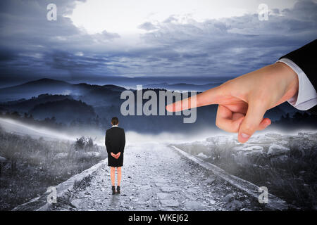 Gigante di puntamento a mano a imprenditrice in piedi con le mani dietro la schiena contro sassoso sentiero di grandi Misty Mountains Foto Stock