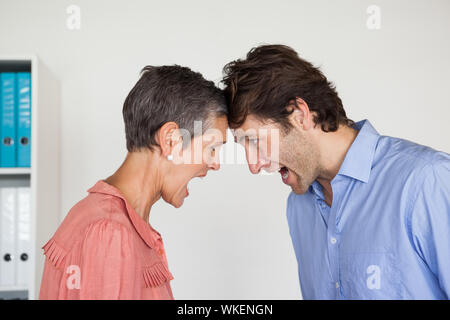 Adirato contro la gente di affari gridando ad ogni altro in ufficio Foto Stock