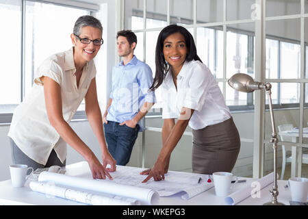 Sorridente architetti piani analizzando insieme in ufficio Foto Stock
