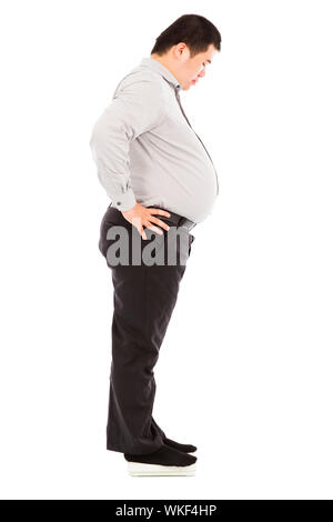 Fat business man standing sulla bilancia Foto Stock