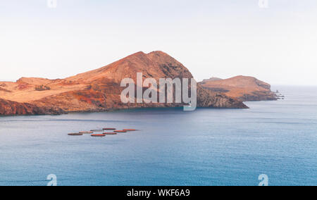 Il paesaggio costiero con allevamento ittico e rocce rosse di Ponta de Sao Lourenco, isola di Madeira, Portogallo Foto Stock