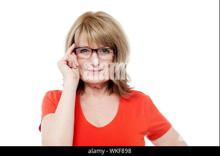 Età della donna regolando i suoi occhiali Foto Stock