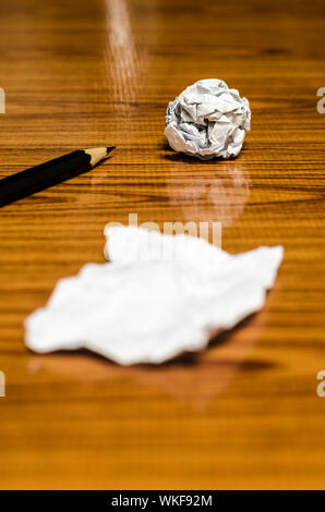 Cascami di carta e accartocciata con matita su uno sfondo di legno Foto Stock