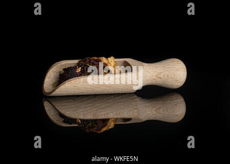 Lotto di pezzi di lingonberry fragole tè con un cucchiaio di legno isolata sul vetro nero Foto Stock