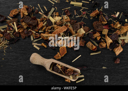 Lotto di pezzi di lingonberry fragole tè con un cucchiaio di legno flatlay sulla pietra grigia Foto Stock