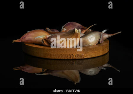 Lotto di pezzi di organico aglio bianco allium sativum sul bambù coaster isolato sul vetro nero Foto Stock