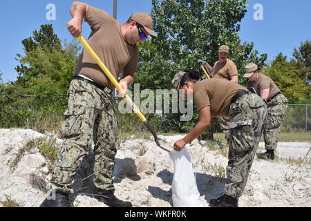 I marinai dalla base navale di attività di sostegno (NSA) Hampton Roads 1° Divisione tenente riempire sacchi di sabbia in preparazione per l'uragano Dorian, 3 settembre 2019. Essi hanno anche eliminato scarichi e controllati per eventuali pericoli di missili intorno alla base. Immagine cortesia Katisha Draughn-Fraguada/Naval attività di sostegno Hampton Roads. () Foto Stock