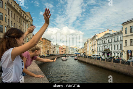 Felice giovani sventolano a turisti sul fiume Moyka, San Pietroburgo, Russia. Foto Stock