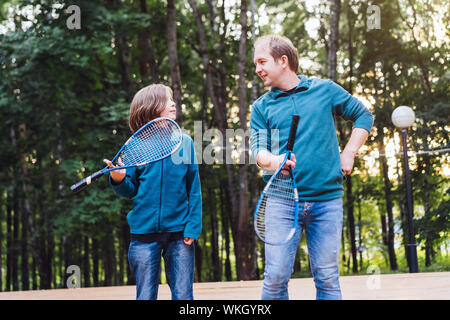 Padre figlio insegna a giocare a badminton nel parco. Week-end per due persone. Foto Stock