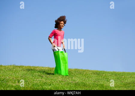 Bambina gioca il sacco di gioco gara sperando di salto Foto Stock