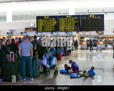 AEROPORTO TUI CHECK-IN CODE PASSEGGERI ANNOIATO BAMBINI VACANZA VOLO RITARDI INFORMAZIONI SCHERMATE CODE ritardate passeggeri code di voli charter vacanza passeggeri e bagagli attendere al terminal dell'aeroporto per il check-in bagagli per il loro volo Spagna Foto Stock