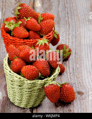 Dolce di fragole di foresta in due cesti di vimini closeup rustico sfondo di legno Foto Stock