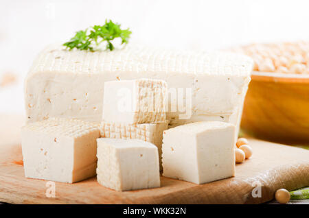 Fagiolo di soia tofu cagliata sul tagliere con tazza di fagioli a parte. Non a base di latte sostituto alternativo per formaggio Foto Stock