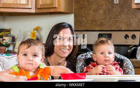 Una madre in cucina pone con neonati Foto Stock