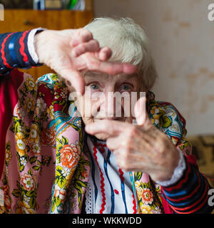 Una donna anziana in abiti brillante mostra dal gesto delle mani photo frame. Foto Stock