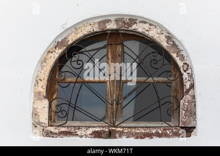 Finestra ad arco in Oia con ferro battuto barre sulla finestra fatiscente Foto Stock