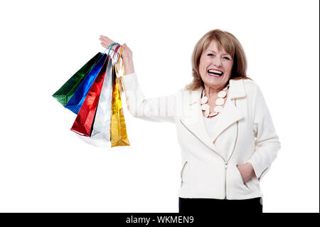 Senior donna le mani alzate con sacchetti colorati Foto Stock