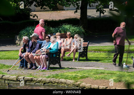 Turisti di rilassarsi e godersi il sole estivo in Trenance Gardens a Newquay in Cornovaglia Foto Stock