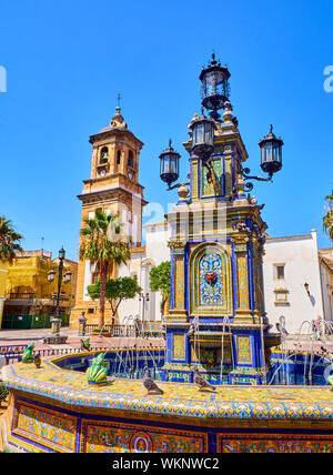 Facciata principale della Parroquia de Nuestra Senora de la Palma parrocchia con la fontana di piastrelle in primo piano. Plaza Alta Square. Algeciras, Spagna. Foto Stock