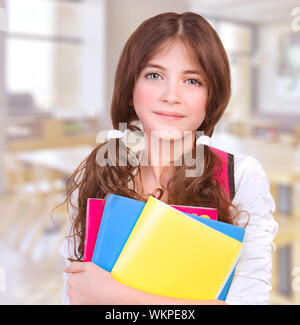 Ritratto di Cute girl teen in piedi in aula con libri colorati in mani, la preparazione alla lezione, torna a scuola, la conoscenza e l educazione Nozione Foto Stock