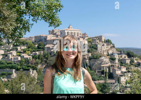 Femmina indipendenti traveler e Gordes bellissimo vecchio villaggio sulla collina circondata da montagne, giovane donna bionda di viaggio in Provenza, Francia Foto Stock