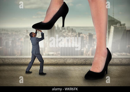 Immagine composita di imprenditrice rafforzamento sul piccolo imprenditore contro il balcone che si affaccia sulla città Foto Stock