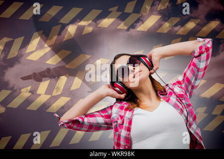 Casual brunette ascoltando musica contro il cielo nuvoloso Foto Stock