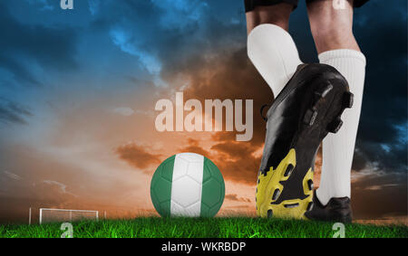 Immagine composita di scarpa da calcio calci nigeria sfera contro erba verde sotto e blu cielo arancione Foto Stock