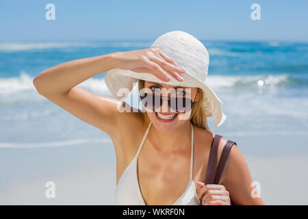 Sorridente bionda in bikini bianco borsa sulla spiaggia in una giornata di sole Foto Stock