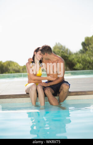 Stupendo paio seduti a bordo piscina sulle vacanze in una giornata di sole Foto Stock