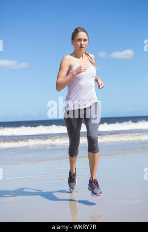 Montare focalizzato bionda jogging sulla spiaggia in una giornata di sole Foto Stock