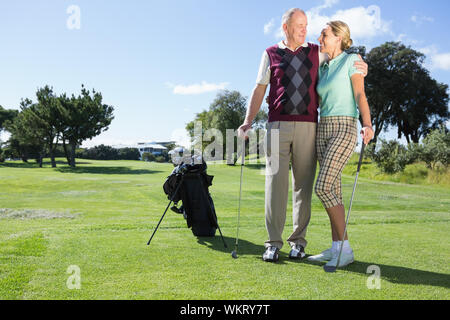 Golf Coppia sorridente permanente a vicenda in una giornata di sole presso il campo da golf Foto Stock