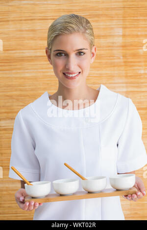 Sorridente terapista di bellezza vaschetta di contenimento dei trattamenti presso il centro termale Foto Stock