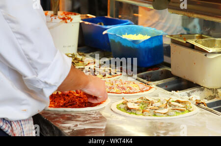 Lo Chef rendendo un assortimento di pizze in un ristorante Foto Stock