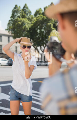 Giovane bella bionda in posa per il suo fidanzato in una giornata di sole in città Foto Stock
