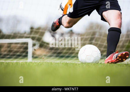 Il portiere calci palla lontano dal traguardo in un giorno chiaro Foto Stock